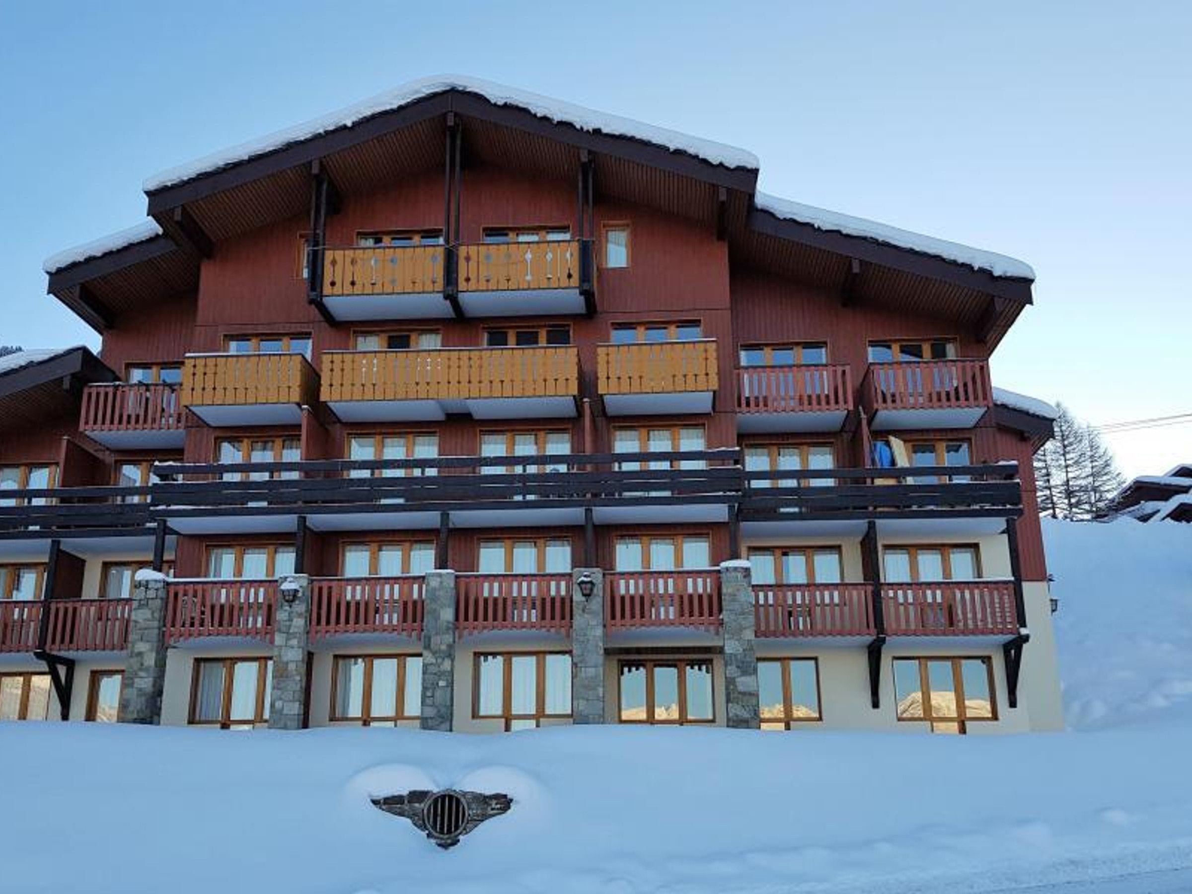 Un hôtel à plusieurs étages, doté de balcons et arborant un emblème représentant le ski.