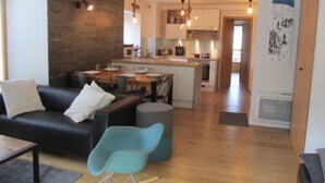 Ein modernes Wohnzimmer mit einem schwarzen Sofa, einem blauen Sessel und einem Holzessttisch.