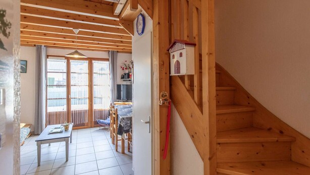 A wooden interior with a staircase, a dining area with a table and chairs, and a view through a glass door. - Apartment T4 for 7, parking, near ski resorts (Luz-Saint-Sauveur)