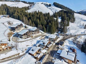 A snow-covered mountain resort with multiple buildings, including a large lodge and smaller cabins, surrounded by dense forests. - Modern apartment near slopes, 6 pers, south balcony, pets allowed, parking, wifi (Notre-Dame-de-Bellecombe)
