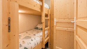Un lit superposé avec un matelas à motifs, une porte en bois avec une poignée et un loquet en métal.