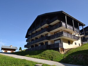 Ein mehrstöckiges Gebäude mit Balkonen, gelegen an einem Hang unter blauem Himmel.