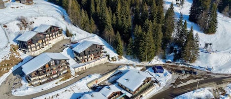 A ski resort with multiple buildings, including a large lodge with balconies and a smaller cabin.