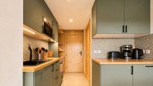 Une cuisine étroite avec des meubles de rangement en bois, un four à micro-ondes, une machine à café et un grille-pain.