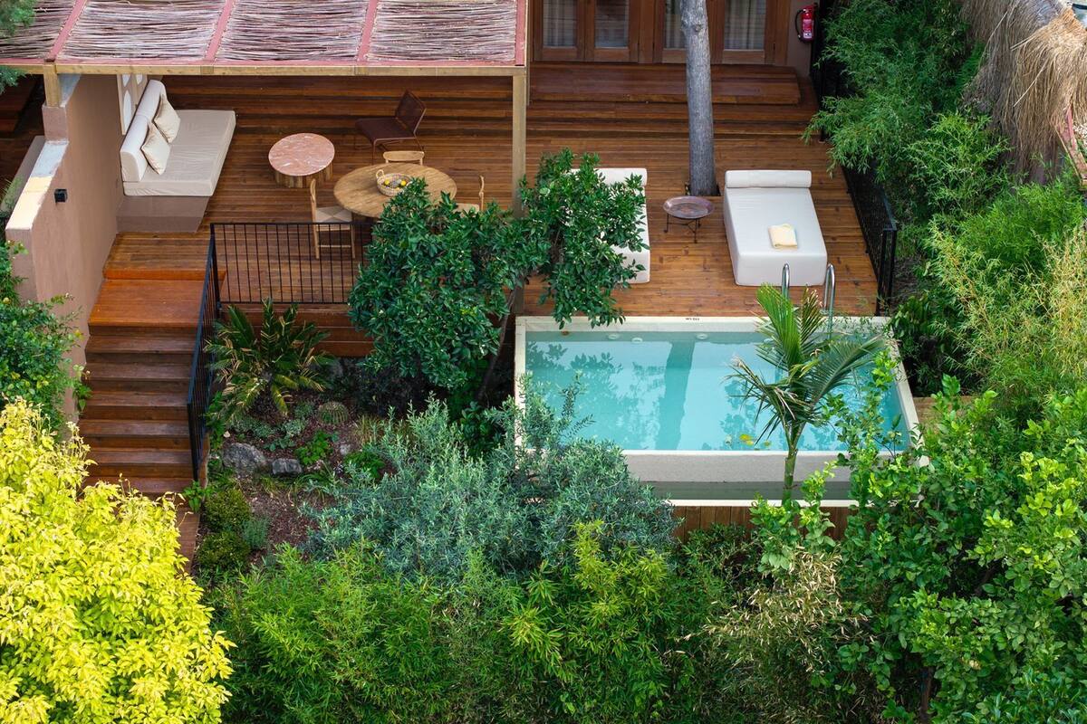 A rooftop pool area with wooden deck, lounge chairs, and a small table.