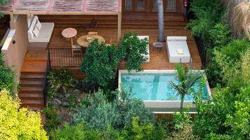 A rooftop pool area with wooden deck, lounge chairs, and a small table.