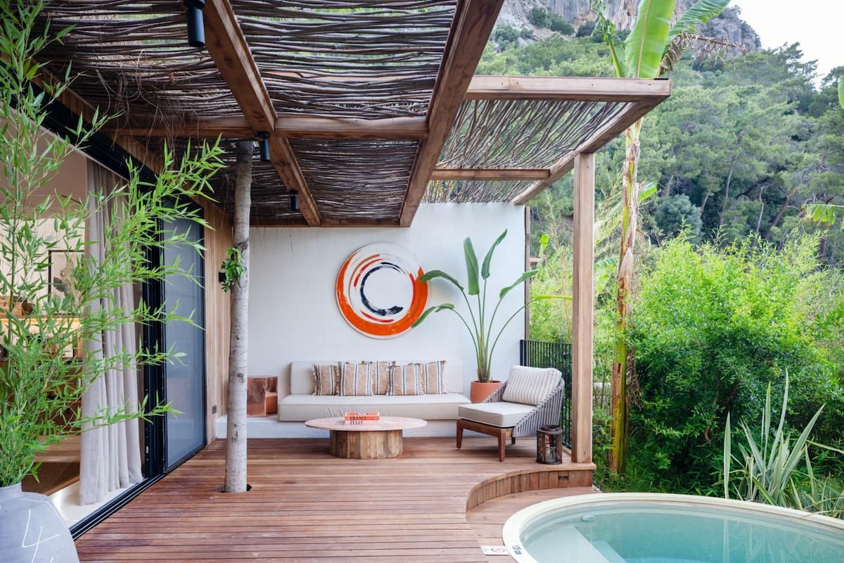A wooden deck with a pool, a sofa, and a potted plant.