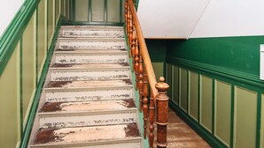 Un escalier dont les murs sont peints en vert et qui possède une main courante en bois.