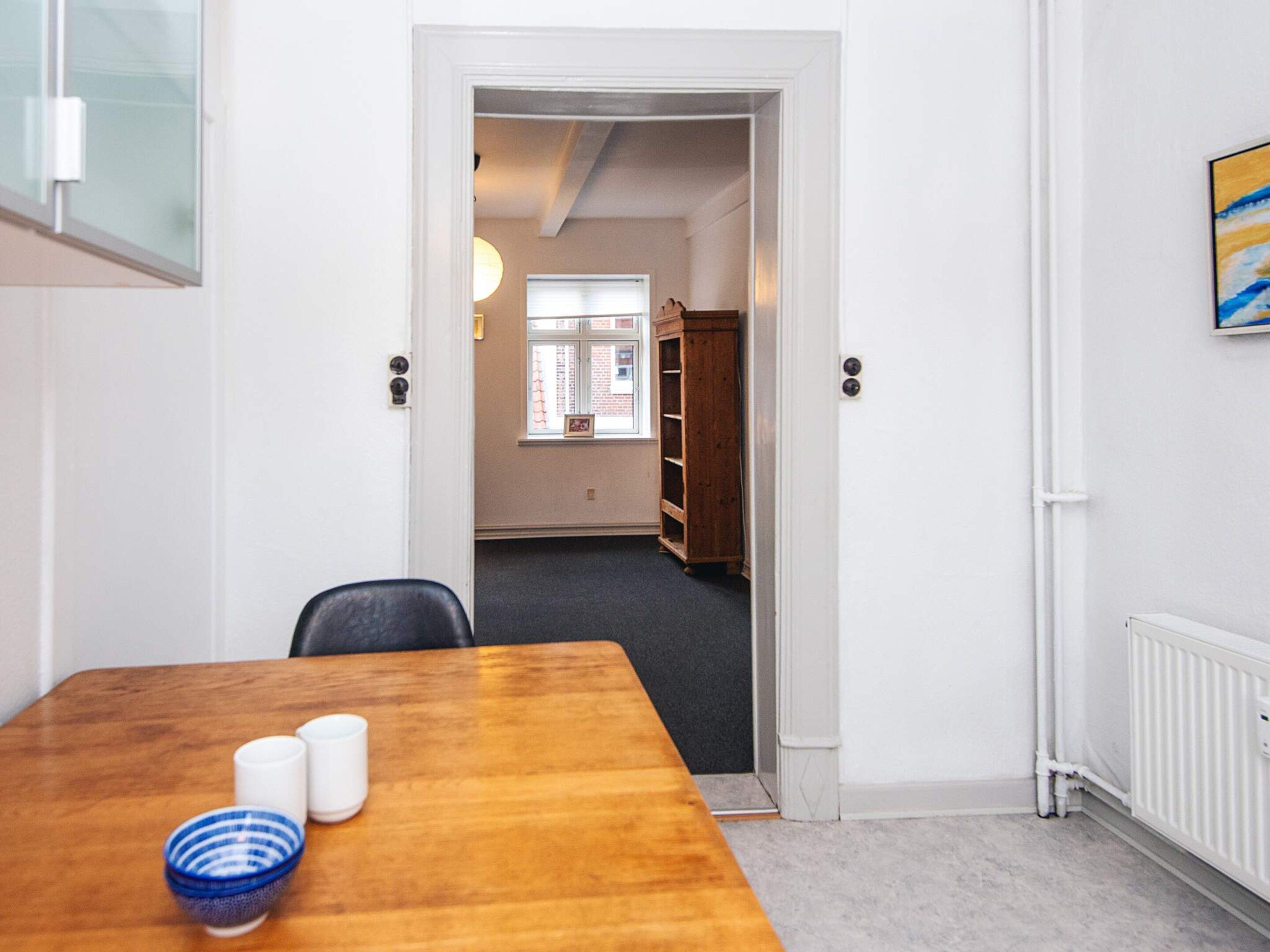 Una habitación con una mesa de madera, dos sillas, un cuenco azul y una taza blanca.