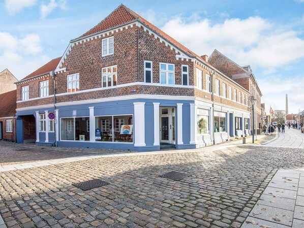 A traditional brick building with a blue facade, large windows, and a cobblestone street.