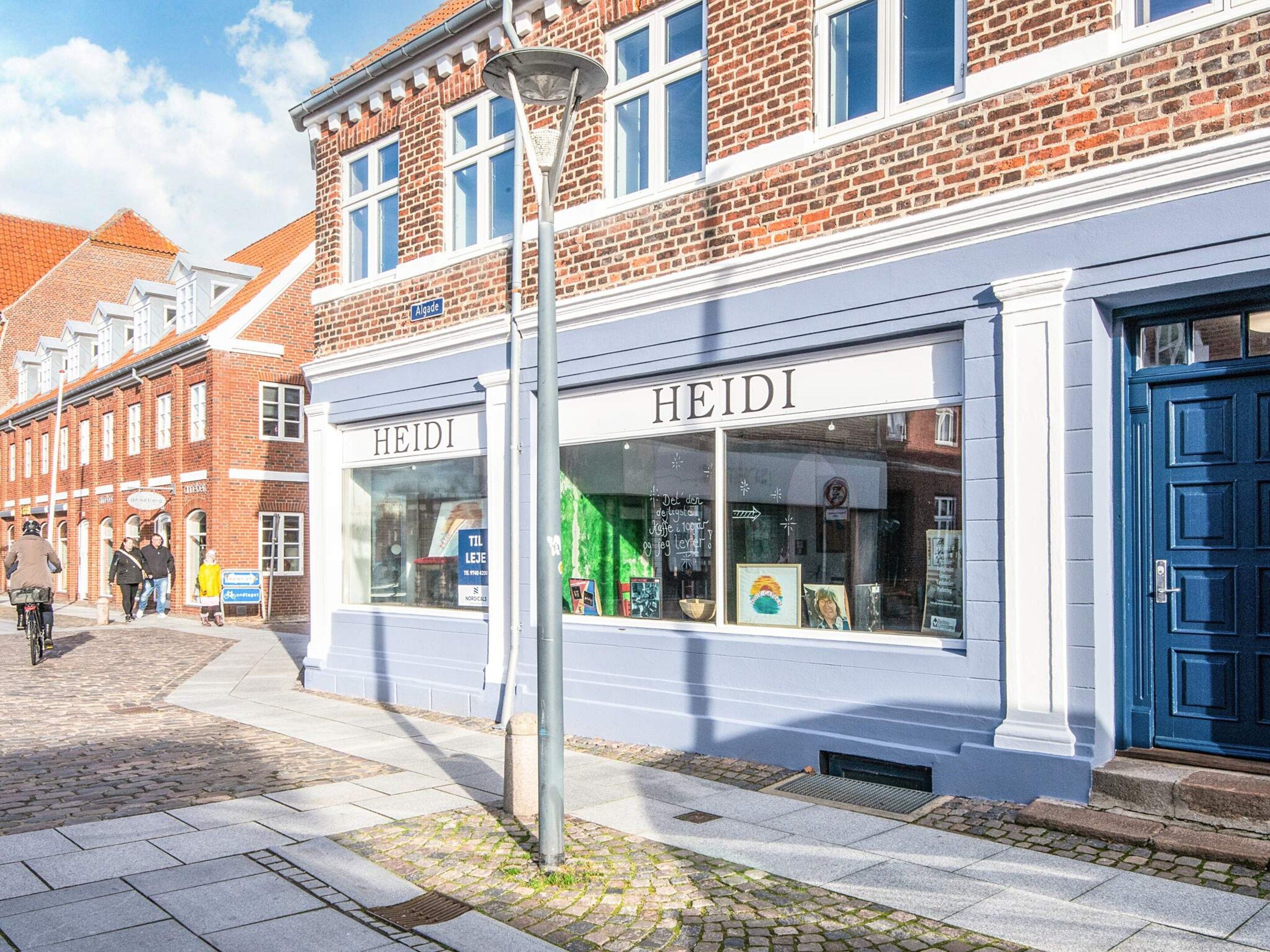Een straatbeeld met een winkel genaamd 'HEIDI', met een blauwe deur en etalage.