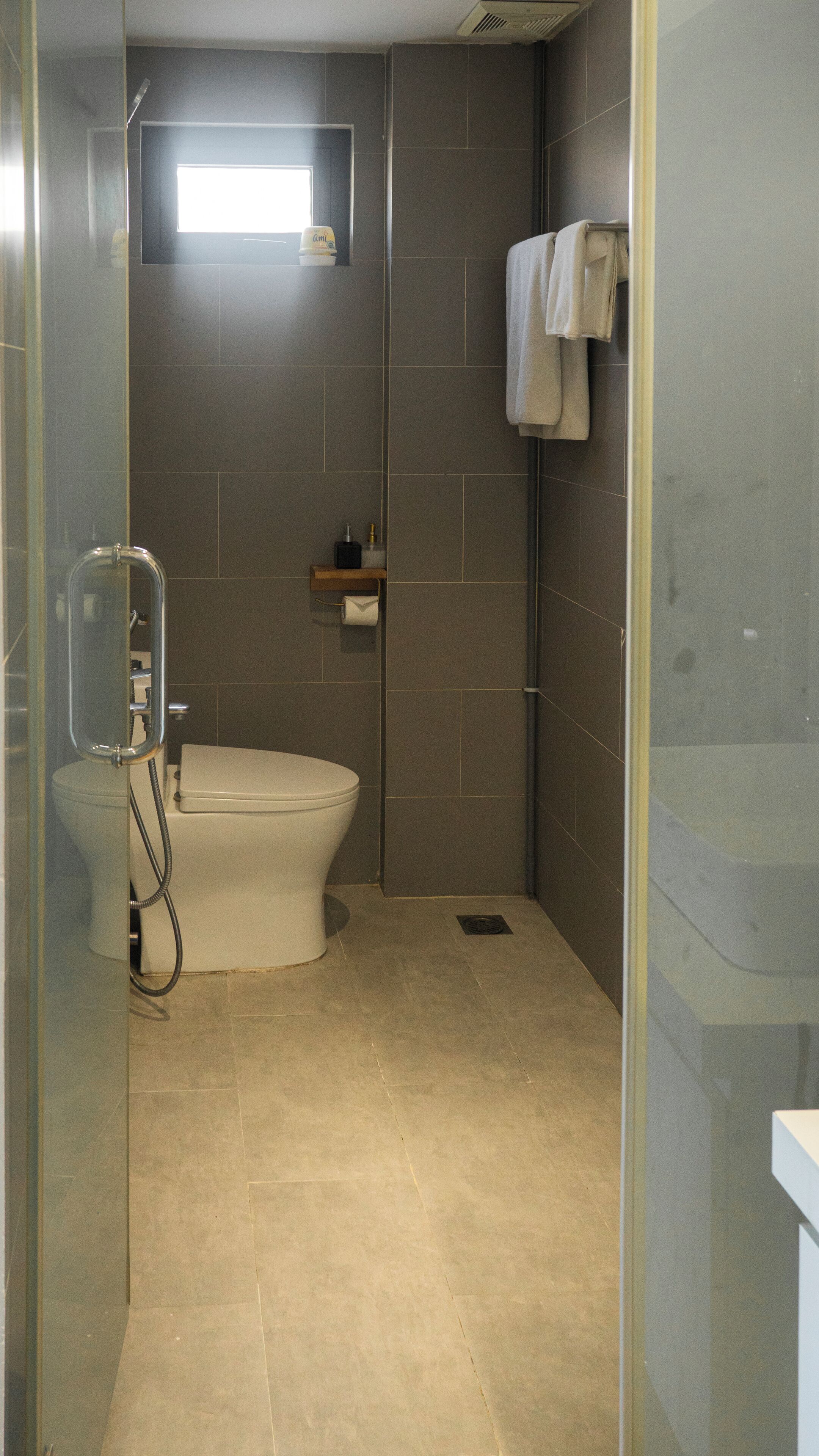 A bathroom with a toilet, a shower enclosure, and a towel hanging on the wall.