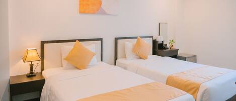Habitación de hotel con dos camas, cada una con una almohada y una mesita de noche con lámpara.