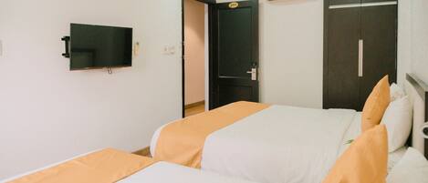 Ein Hotelzimmer mit zwei Betten, einem Fernseher, einem Kleiderschrank und einer Klimaanlage.