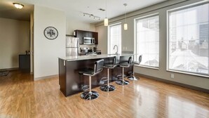 A modern kitchen with a central island, bar stools, and large windows.