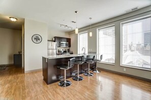 A modern kitchen with a central island, bar stools, and large windows.
