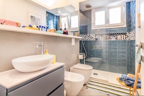 Un baño moderno con un lavamanos grande de color blanco, un inodoro y una zona de ducha.