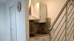A compact kitchen with white cabinets, a stainless steel sink, and a patterned backsplash. - Ortigia Sweet Home in Syracuse (Syracuse)