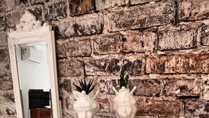A white dresser with two decorative vases against a brick wall. - Ortigia Sweet Home in Syracuse (Syracuse)