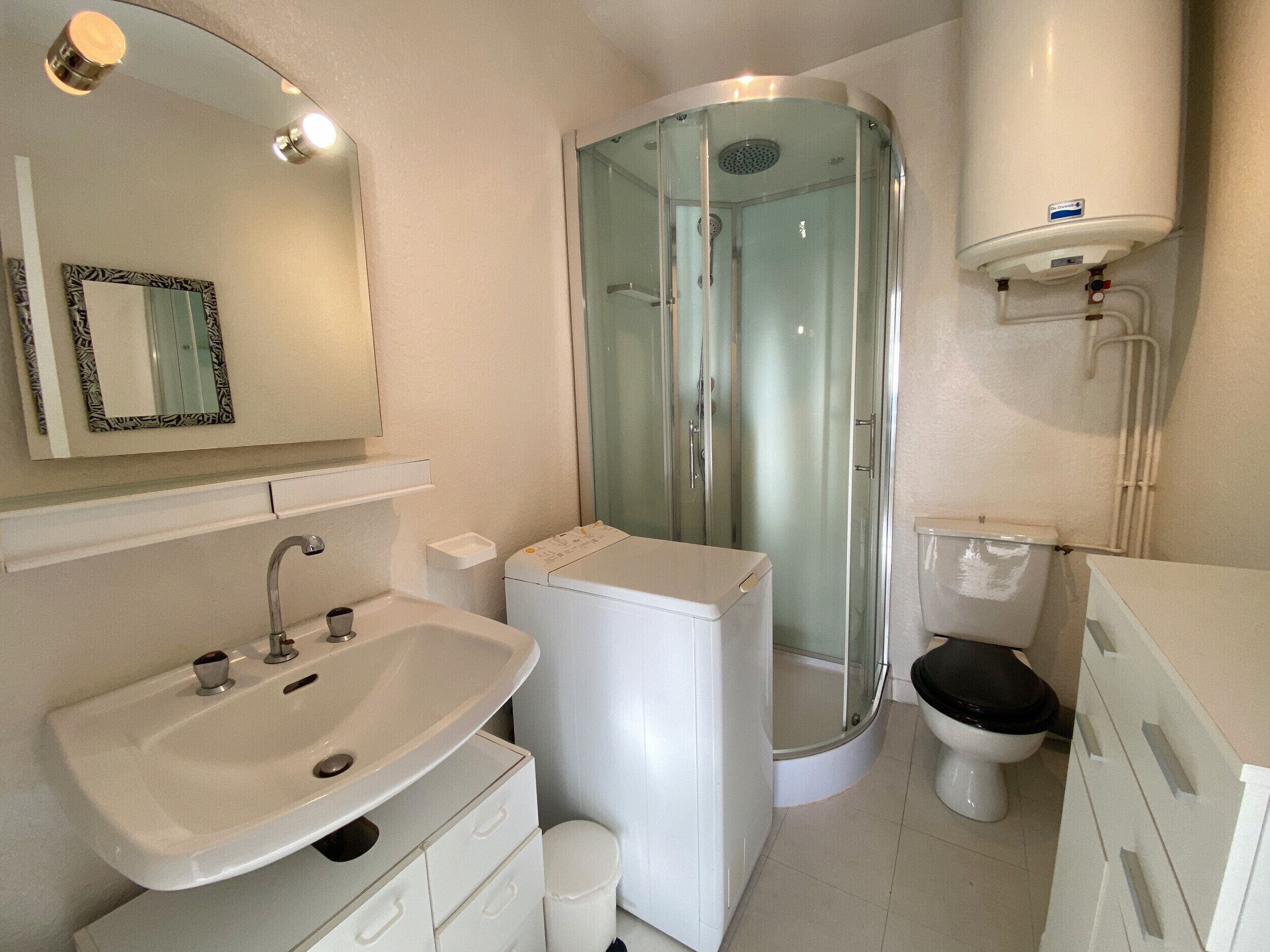 A modern bathroom with a glass-enclosed shower, a white sink, and a toilet.
