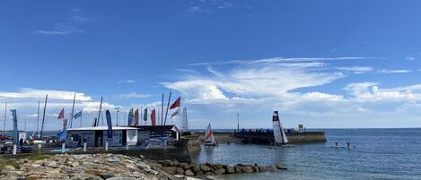 A marina with boats and flags, a pier extending into the water, and a rocky shoreline.