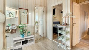 Ein Zimmer mit Holzwänden, einem weißen Konsolentisch mit Topfpflanze, einem Spiegel und einem Bett mit Kopfteil.