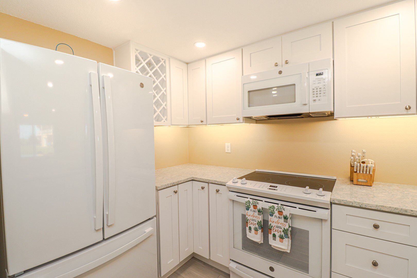 Una cocina compacta con armarios blancos, un microondas integrado, una estufa y un refrigerador.