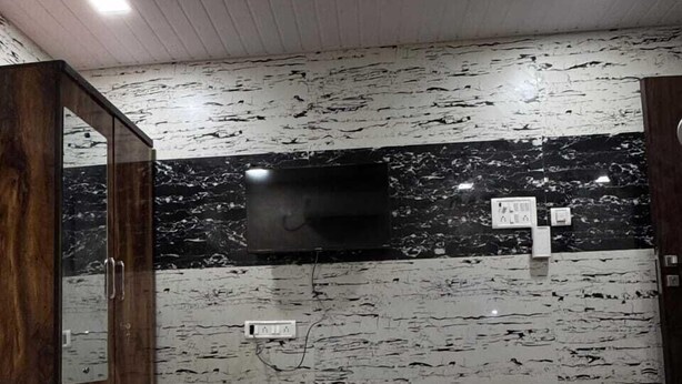 A hotel room with a bed, a television mounted on the wall, and a wooden wardrobe. - Hotel The Sunset Avenue (Mumbai)