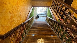 A grand staircase with a marble floor and ornate golden railings, leading to a door labeled "STAFF". - Hotel The Sunset Avenue (Mumbai)