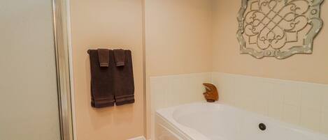 A bathroom with a bathtub, a shower, and two towels hanging on the wall.