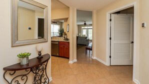 A hallway with a dining area, kitchen, and a closed door.