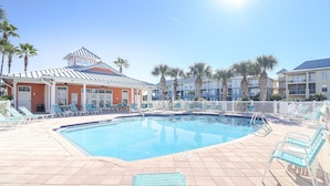 A swimming pool with lounge chairs and a building with a sloped roof.