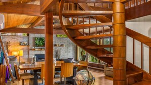 A spacious living area with a wooden spiral staircase, a fireplace, and a globe in the center. - Puzzle Point Lodge in Poulsbo (Poulsbo)