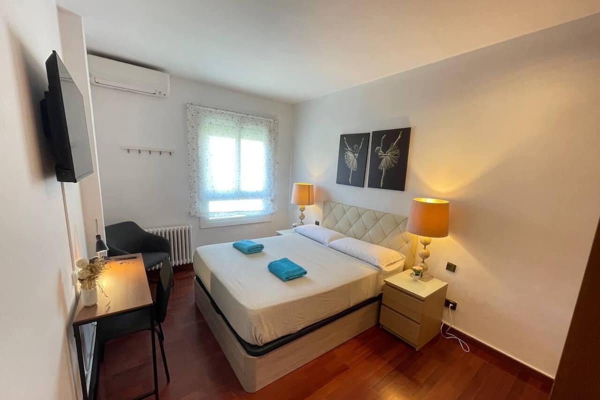 Un dormitorio con cama, mesitas de noche, escritorio y silla.