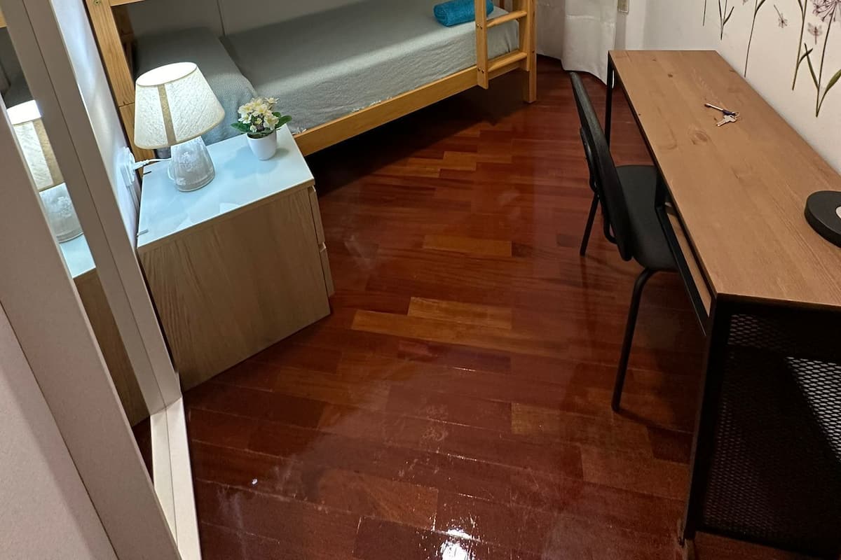 Una habitación compacta con una litera, un escritorio pequeño con lámpara y una silla.