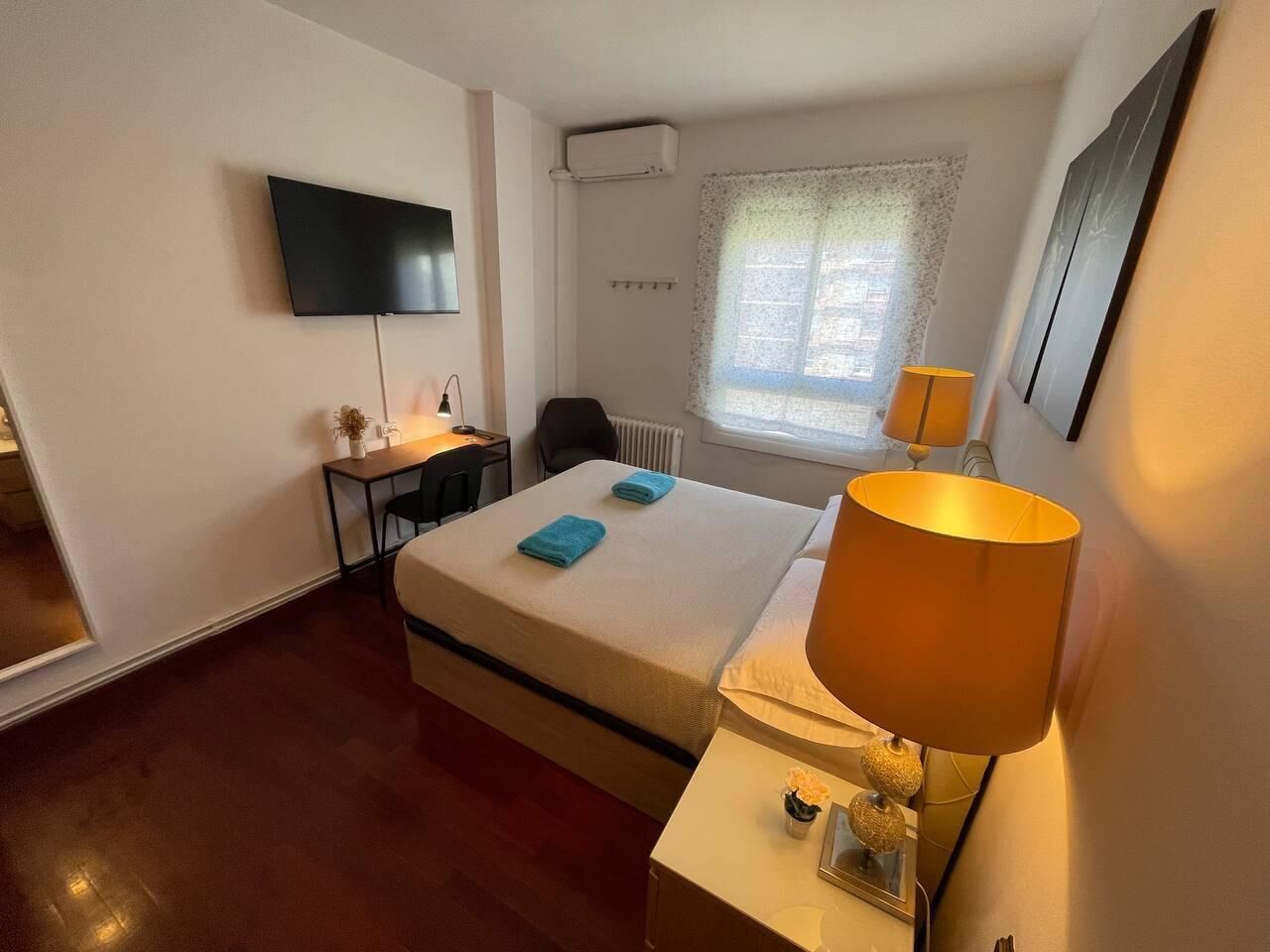 A hotel room with a bed, a desk, a chair, a TV, and a window with a view.