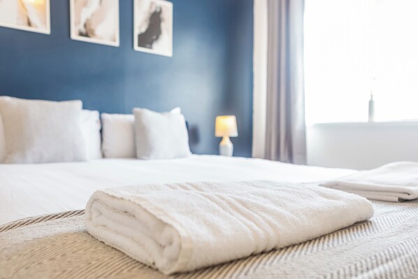 A neatly made bed with a folded white towel in a hotel room.
