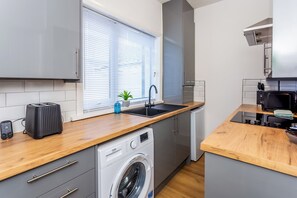 Ett litet kök med tvättmaskin, brödrost och diskho.