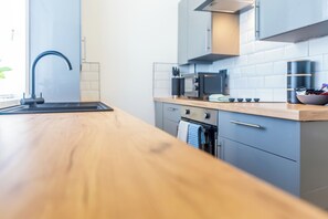 Ett modernt kök med en bänkskiva i trä, rostfria vitvaror och en inbyggd ugn.