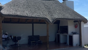 A building with a thatched roof and a tiled patio area. - Zoe & Saint (Cape Town)
