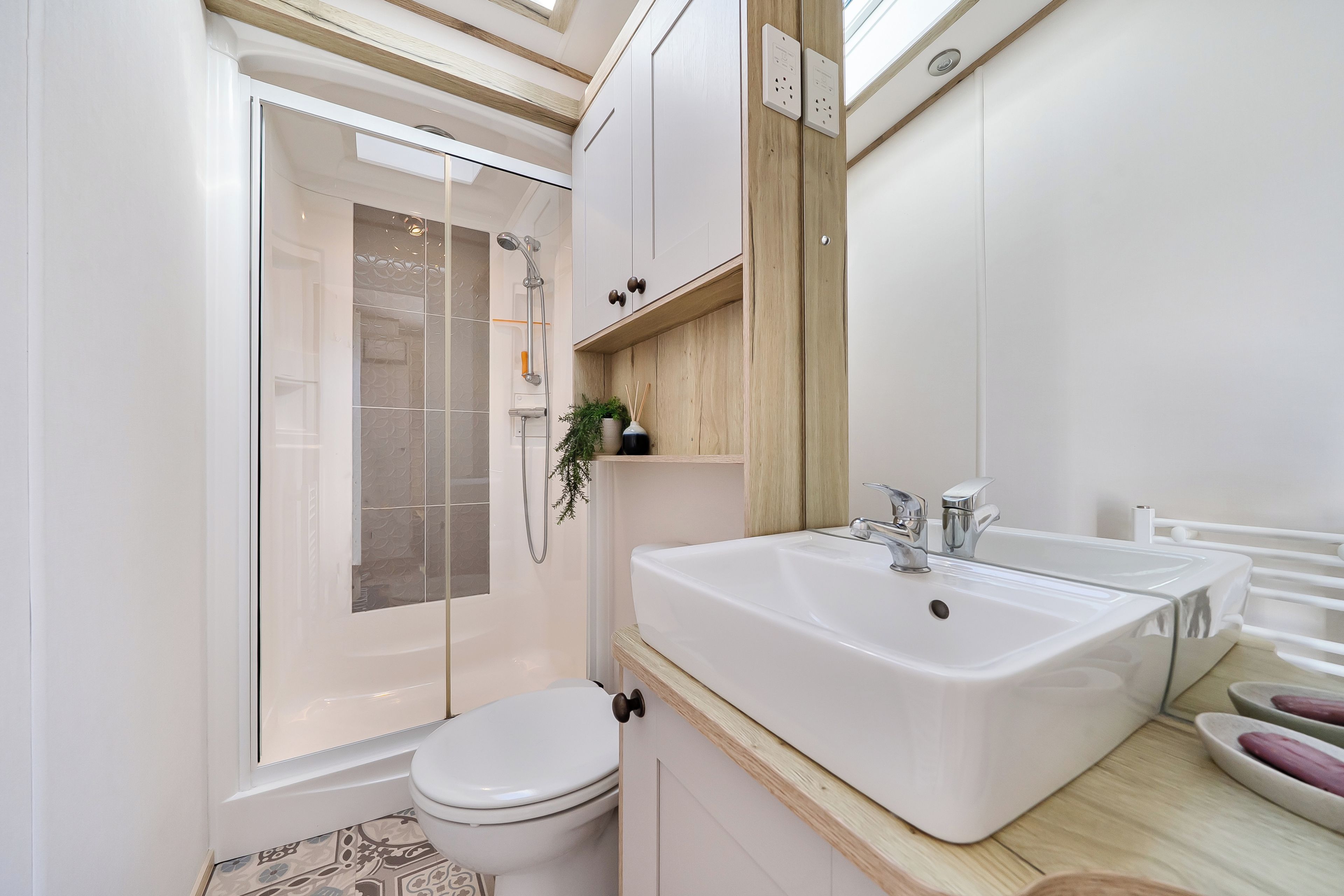 A modern bathroom with a glass-enclosed shower, a white toilet, and a large sink with a mirror above it.