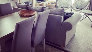 A modern living room with a sofa, chairs, a television, and a dining table.