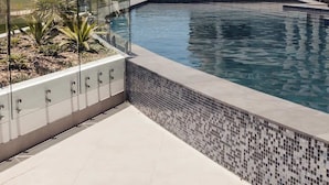 Moderni rakennus, jossa on uima-allas. Uima-altaan ympärillä on lasiaita ja laatoitettu terassi.