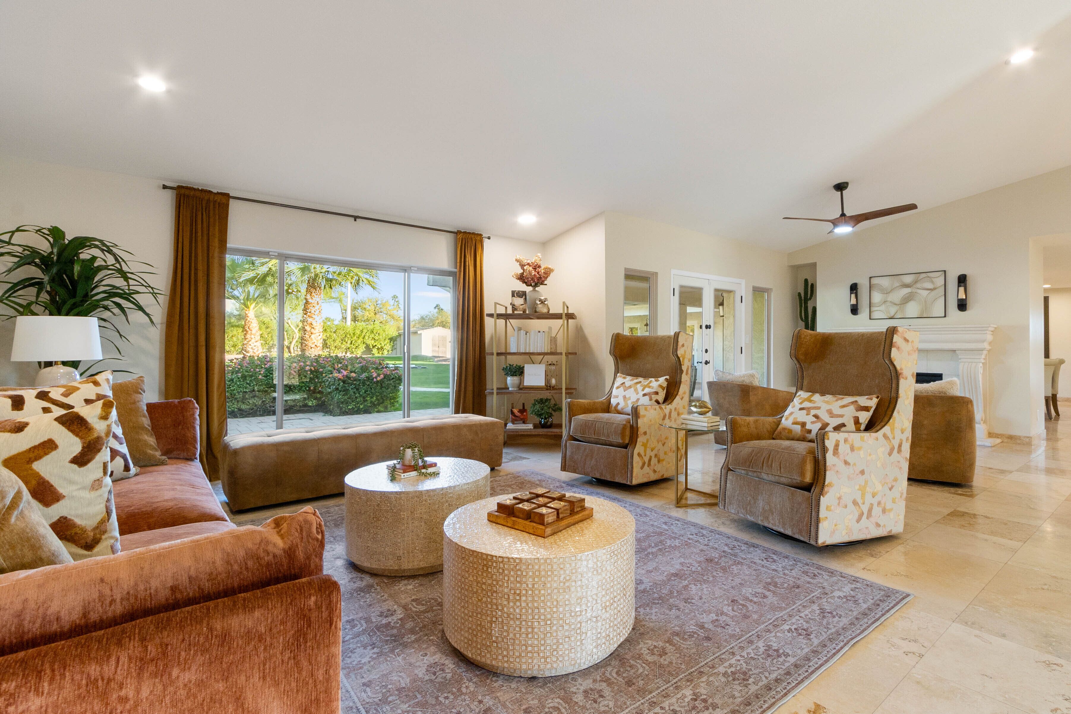 A spacious living room with a large window, a fireplace, and a ceiling fan.
