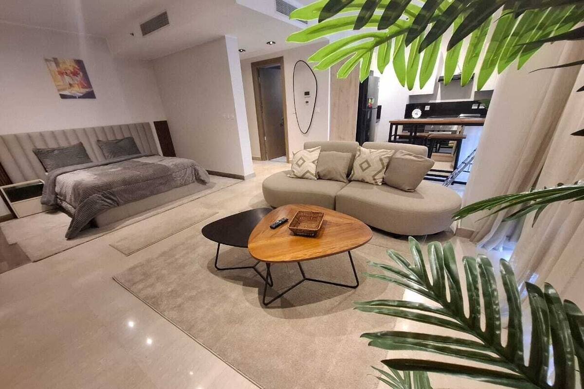 A modern living room with a sofa, a coffee table, and a bed.