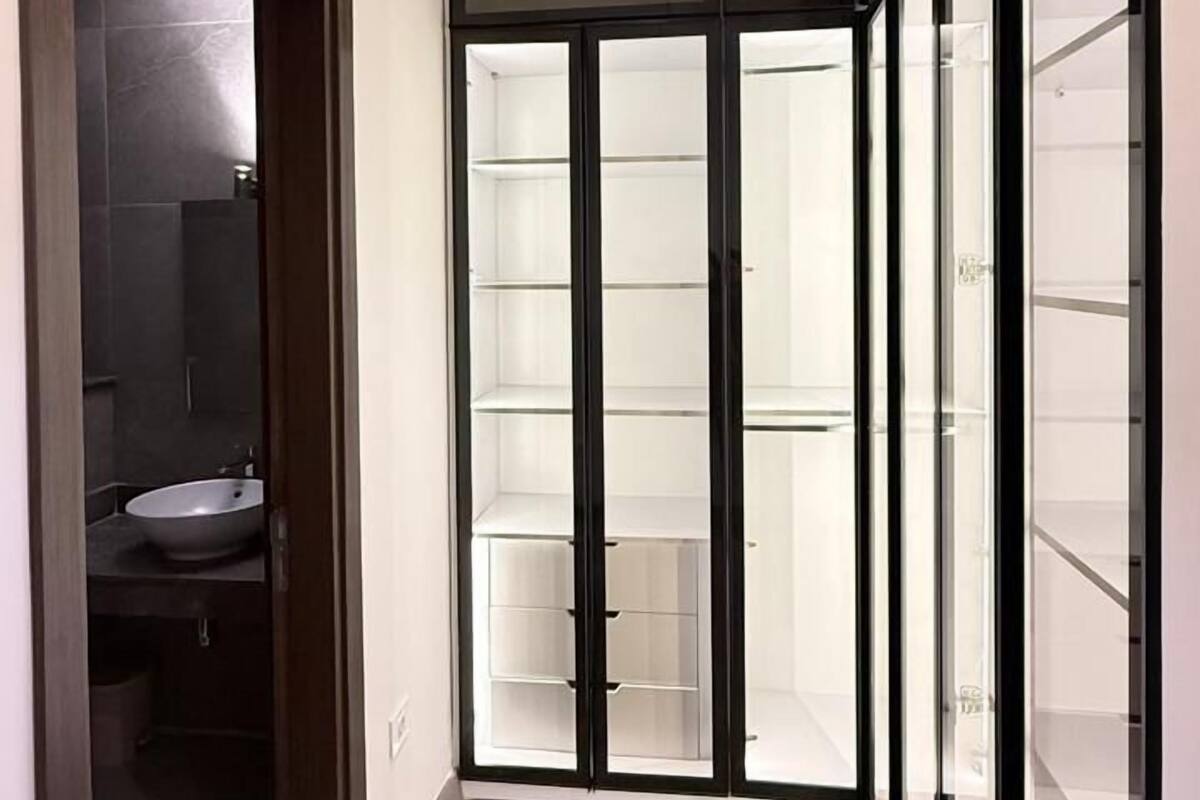 A hallway with a modern light fixture, a glass door with a black frame, and a wooden floor.