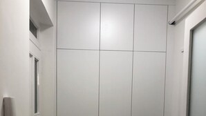 A closed white door with a handle, a white wall-mounted phone, and a window with a partially visible view. - Cozy studio in beautiful Budapest with WiFi, AC (Budapest)