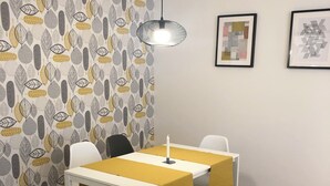 A dining area with a white table and yellow tablecloth, wooden chairs, a bench, and a patterned wallpaper. - Cozy studio in beautiful Budapest with WiFi, AC (Budapest)