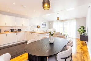 Una cocina moderna con armarios blancos, una mesa de comedor de madera oscura y un jarrón con flores blancas.