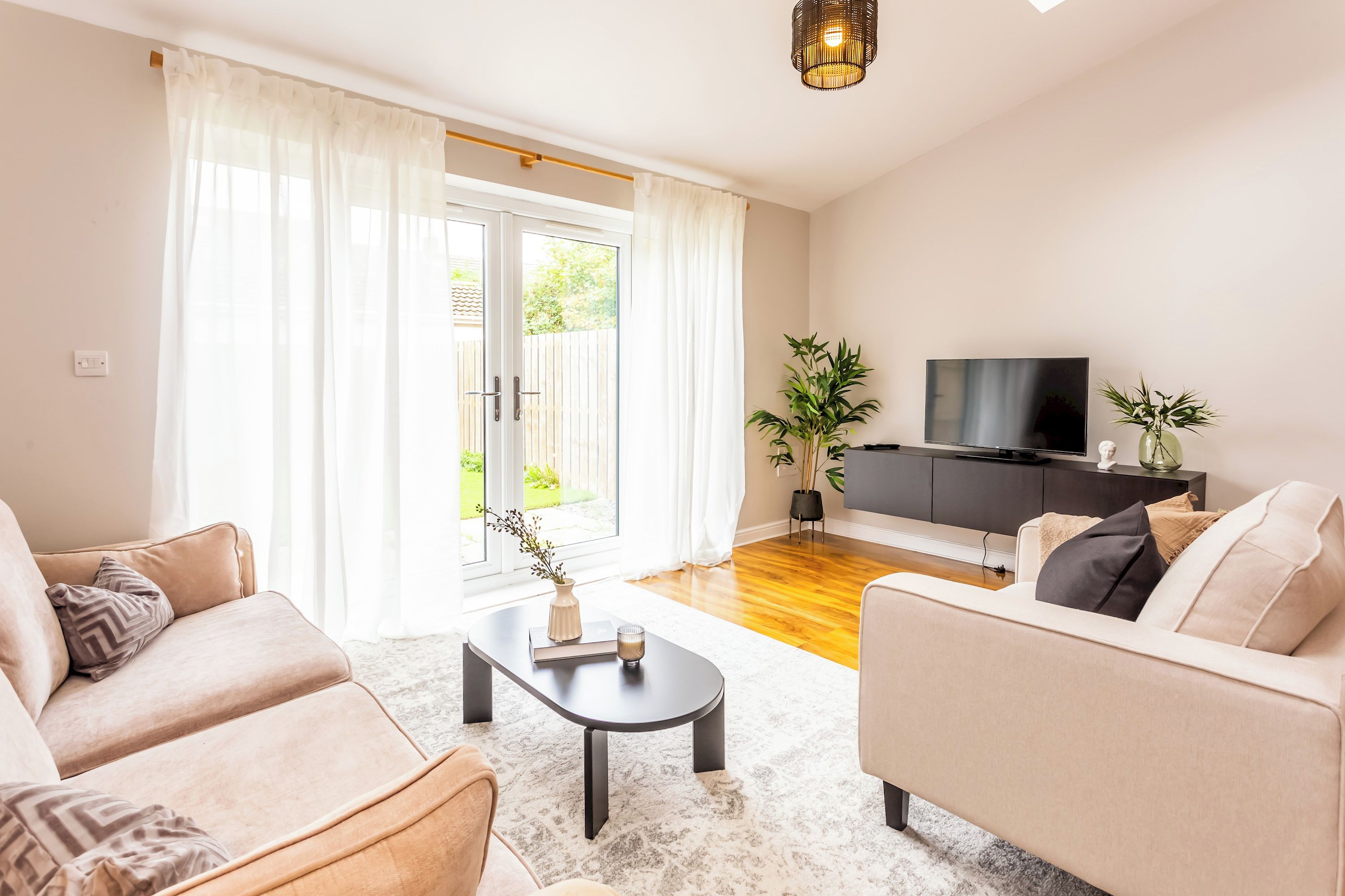 A living room with a sofa, a coffee table, a television, and a plant.